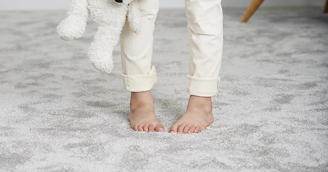Child standing barefoot on a soft, deep-pile residential carpet